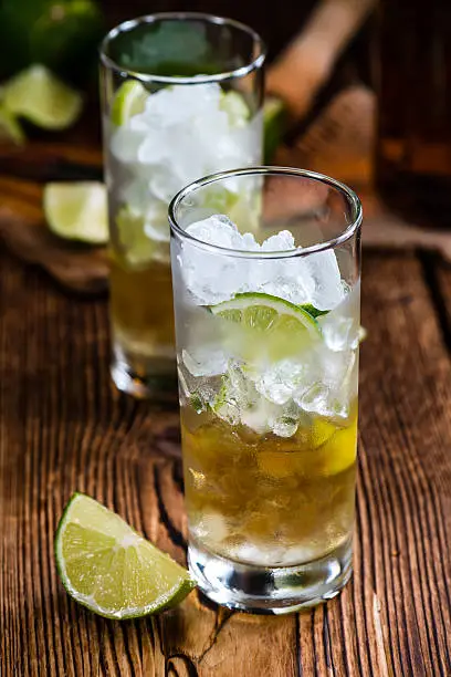 Rum on the rocks (for a Cuba Libre longdrink)  on wooden background