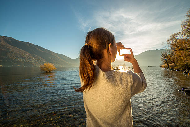 istock Young woman by the lake making a finger frame 499752084