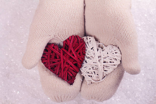 istock Female hands in white knittedmittens holding two hearts 499752948