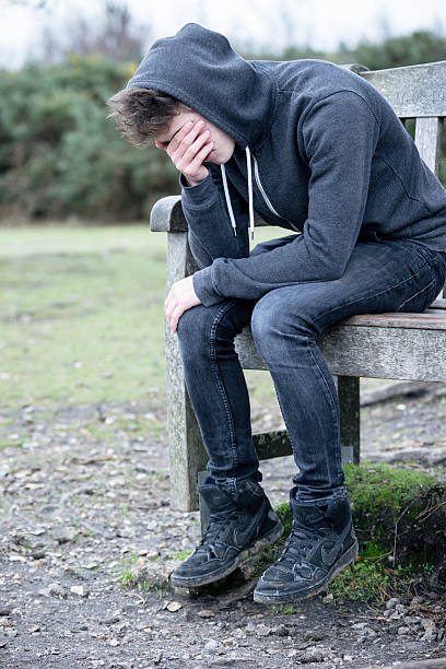 istock Sad Teenage Boy Sitting on A Bench 499754056