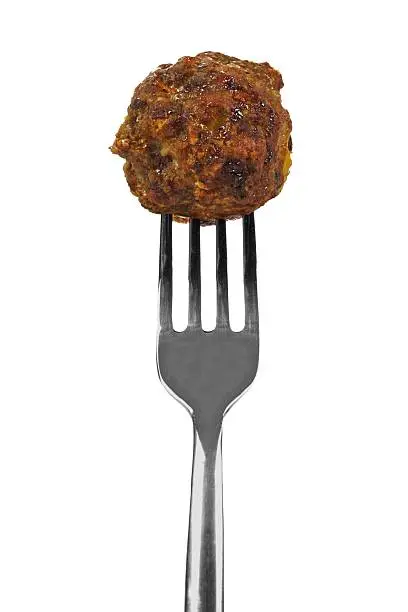 Freshly cooked meatball on a silver fork isolated on a white background.