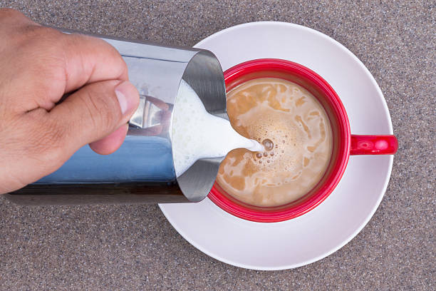 istock Hand of a man pouring milk into black coffee 499757229