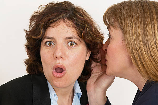 two women whisper a secret stock photo