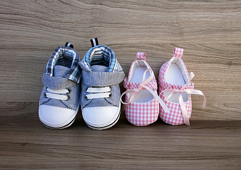 Baby boy and girl shoes on wooden background