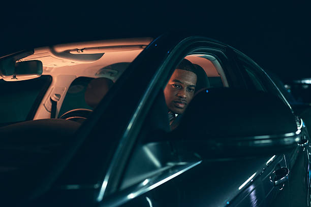 istock Young man looking in side mirror of car at night. 499768138
