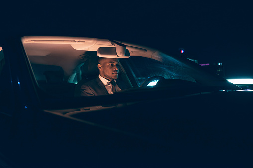 Young businessman in car at night.