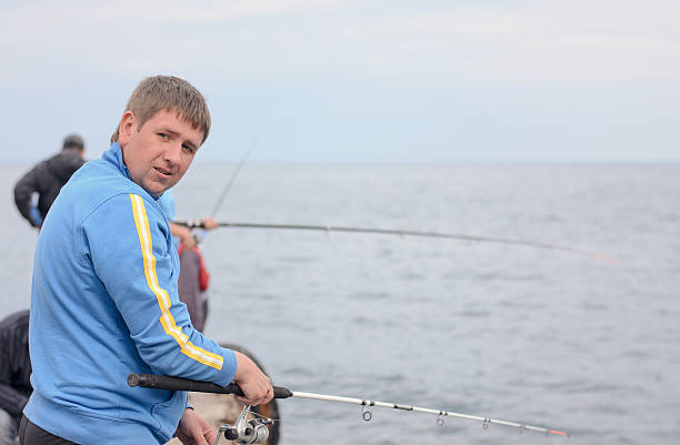 istock Man fishing from a jetty with friends 499771592