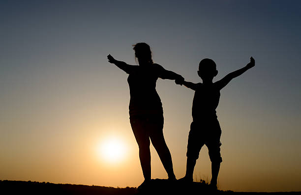 istock Mother and son silhouetted by the setting sun 499773636