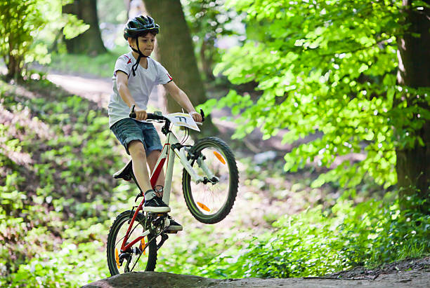 Mountain bike jump Mountain biker races and jumps over a hill and is with one wheel in the air bicycle stunts stock pictures, royalty-free photos & images
