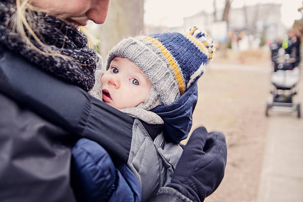 Mother with baby in carrier, outdoors in winter. stock photo