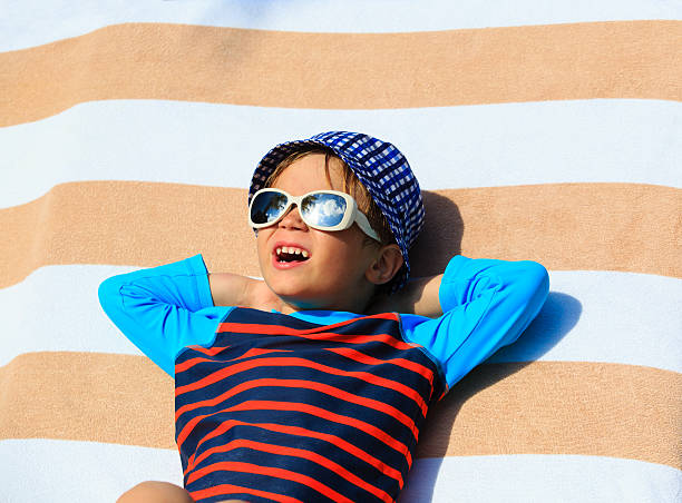 istock cute little boy lying on towel at beach 499778512