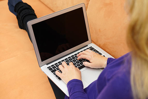 istock Closeup of young woman using laptop on couch 499778891