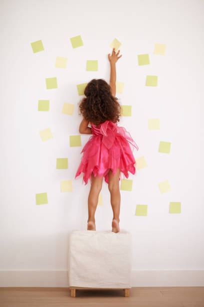 This wall needs some sprucing up Rear view shot of a little girl sticking notes to the wallhttp://195.154.178.81/DATA/i_collage/pi/shoots/783530.jpg tiptoe stock pictures, royalty-free photos & images