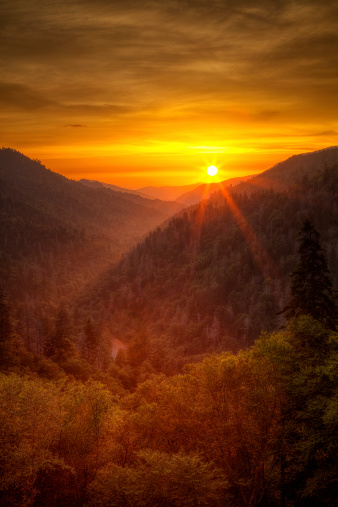 The sun breaking through clouds and setting over the Morton Overlook in the Great Smoky Mountains National Park.