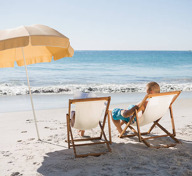 istock Cute couple sunbathing on their deck chairs 499785353