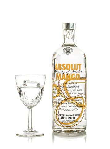 Miami, USA - October 8, 2015: A served glass and bottle of Absolut Mango flavored vodka, isolated on white background.