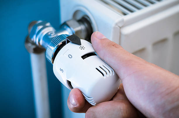 istock One hand adjust thermostat valve close up 499804564
