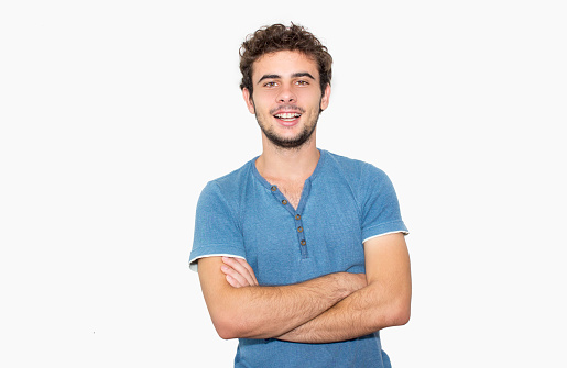 Laughing teenage boy against isolated on white. Young man standing in front of isolated on white and looking at camera with positive emoton. Horizontal composition. Smiling young man wearing a blue t-shirt. Studio shot. Edited from Raw format.