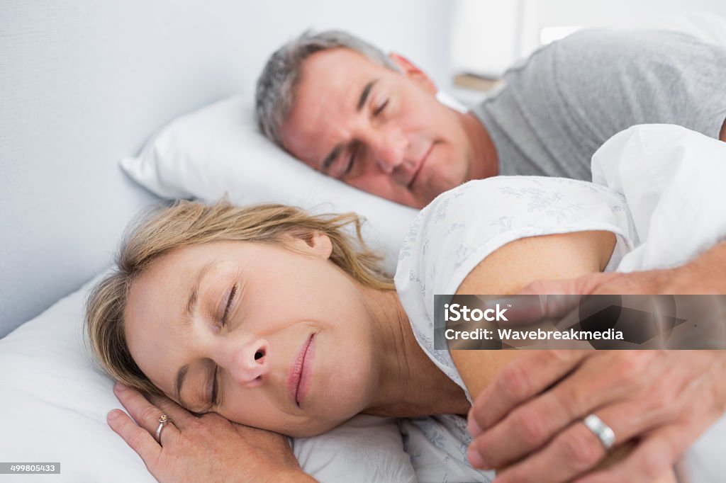 Calm couple sleeping and spooning in bed Calm couple sleeping and spooning in bed in bedroom at home 40-49 Years Stock Photo