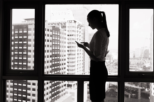Silhouette of businesswoman using her phone in the office.
