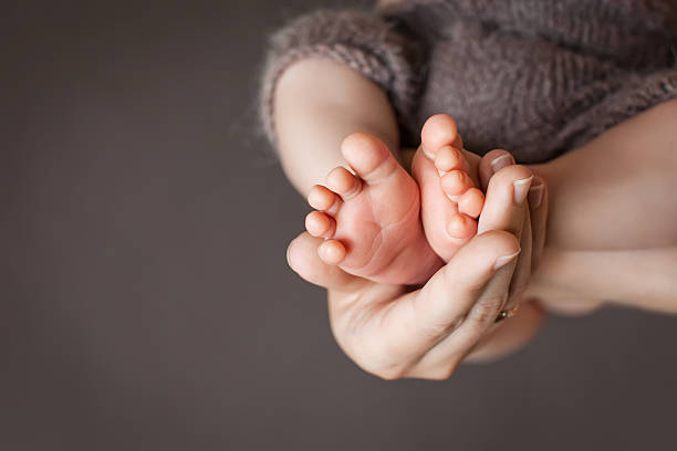 Baby feet in mother hands. Mom and her Child. stock photo