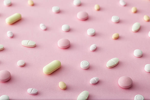 vereinzelt tabletten auf rosa hintergrund - pink pill stock-fotos und bilder