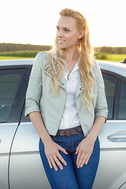 istock Beautiful young woman looking away while standing by car 499841723
