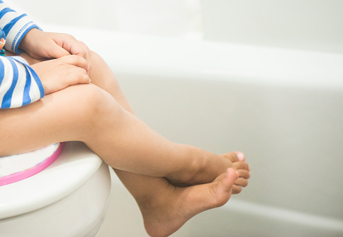 A potty training toddler sitting on a comode