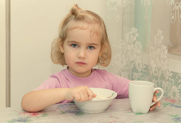 istock Little girl eats porridge from sitting at the table. 499850754