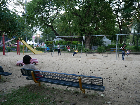 Bangkok, Thailand – December 4, 2015: Children play in a playground inside a public park of Bangkok. Their parents look after them when these kids are playing. 