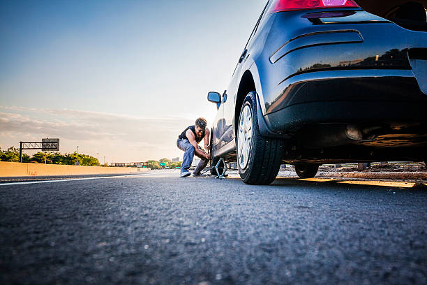 Man changing the flattened tyre at the highway Man changing the flatten tyre at the highway flat tire stock pictures, royalty-free photos & images