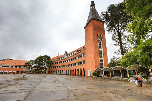 Da Lat city, Vietnam - November 8, 2015: a traveler is visiting the DaLat Teacher College. The school was founded in 1927 France, by architect Moncet designed and directed the construction. Row class built an arc, bare brick red brick school was being transported from Europe to, roofing tiles from France.