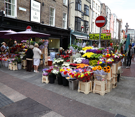 Dublin,Ireland-16th June 2015:A female florist sitting beside her market stall selling freshly cut flowers to members of the public on Duke St,Dublin,Ireland