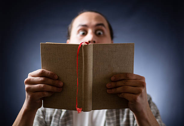 istock young man reading a book in the dark 499885598