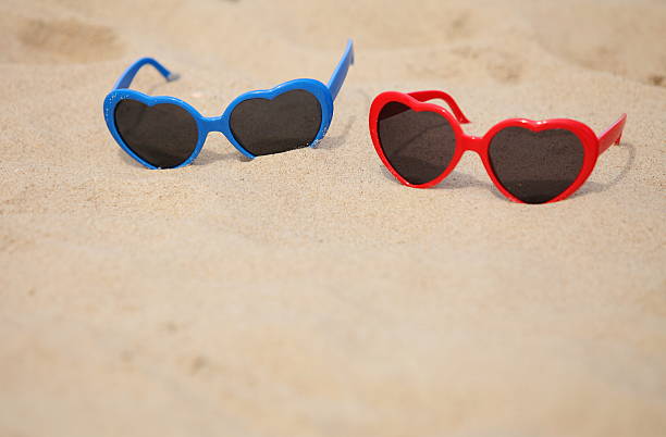 istock Colorful sunglasses shaped heart on the sand 499890749