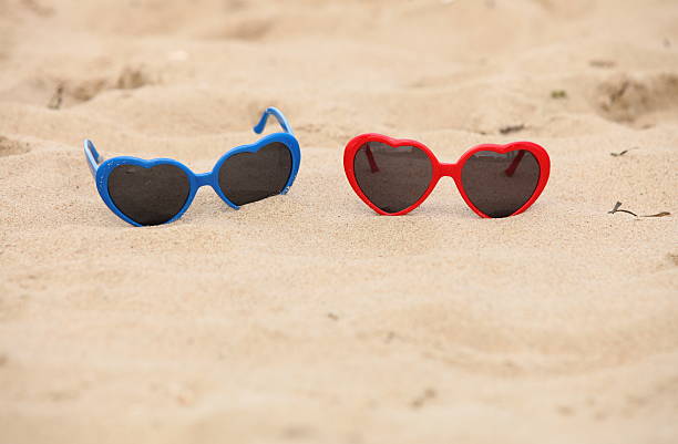 istock Colorful sunglasses shaped heart on the sand 499890943