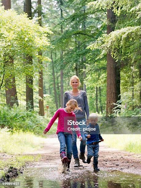 Family Walk In The Woods Stock Photo - Download Image Now - Jumping, Puddle, Women