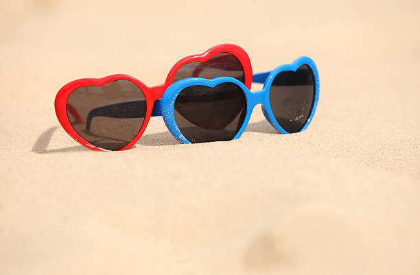 istock Colorful sunglasses shaped heart on the sand 499893243