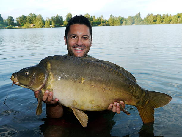 istock Smiling fisherman with his beautiful mirror carp 499893319