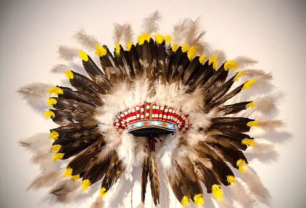 An Indian headdress with eagle featheres and on a white background.