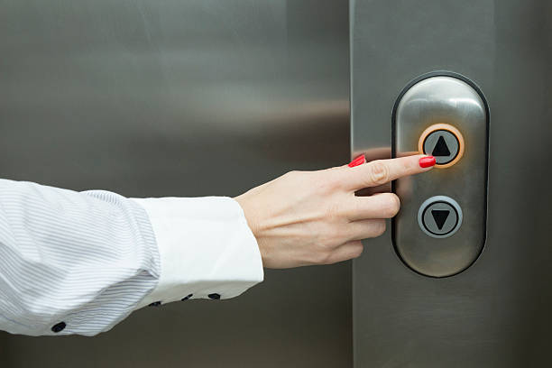 Female hand pressing elevator up button : Woman pressing the elevator button with her forefinger. hand elevator stock pictures, royalty-free photos & images