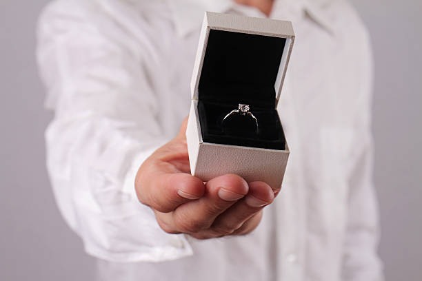 istock Man holding gift box with engagement ring. 499907984