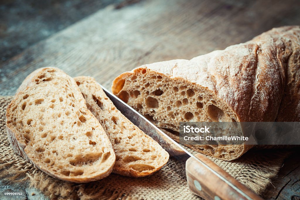 Fresh bread slice and cutting knife on table Fresh bread slice and cutting knife on rustic table Baguette Stock Photo