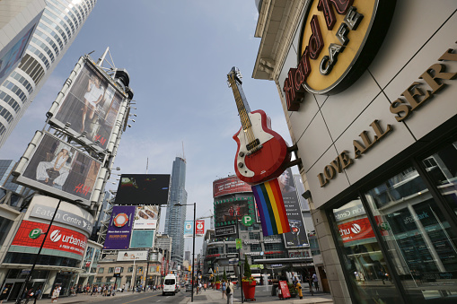 Toronto, Canada - June 24, 2014: Yonge Street, Downtown Toronto. A Pride rainbow flag hangs on Yonge Street during WorldPride 2014. Yonge-Dundas Square is a prime venue for festivals and outdoor events downtown. Pedestrians and traffic on a summer morning near Toronto Eaton Centre.