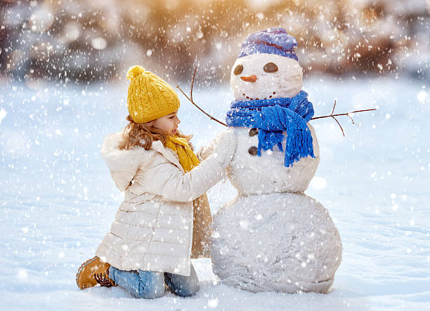 istock girl playing with a snowman 499910100