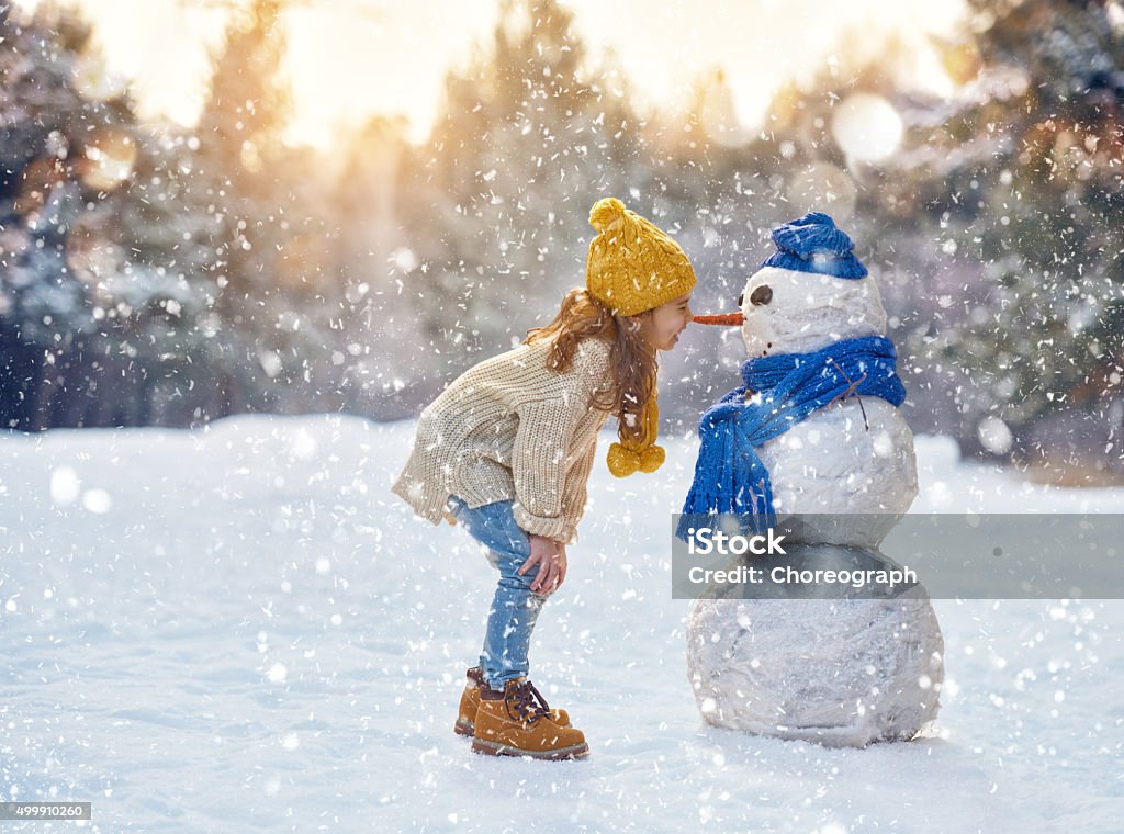 Niña jugando con un muñeco de nieve - Foto de stock de Niño libre de derechos