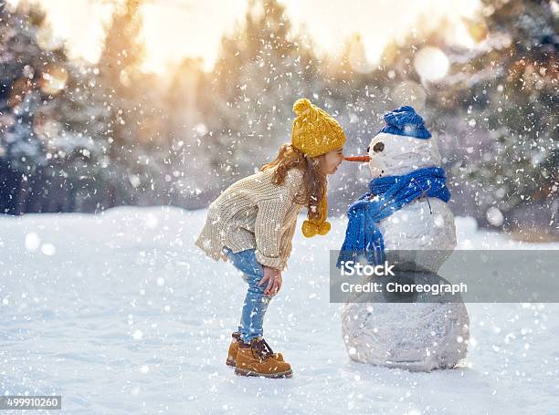 Niña Jugando Con Un Muñeco De Nieve Foto de stock y más banco de imágenes de Niño - Niño, Invierno, Nieve