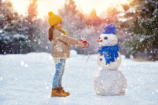 istock child girl plaing with a snowman 499910528