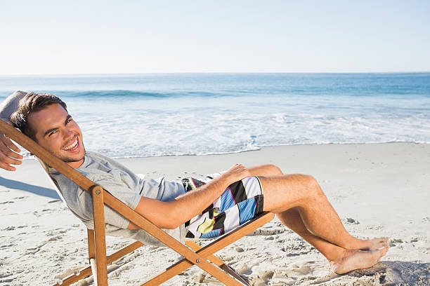 istock Handsome man lying on his deck chair smiling at camera 499910889