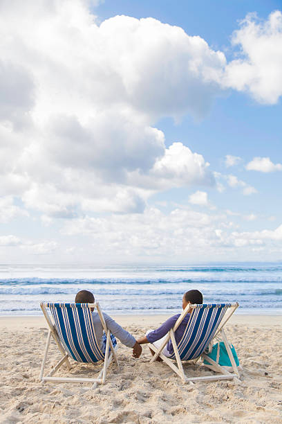 istock African couple sitting on beach chairs at the beach 499914331